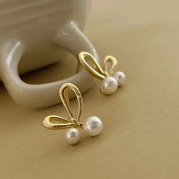 Close-up golden bow earrings with pearl shine detail